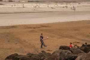 young man on beach practicing hurling